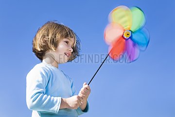Little girl with a windmill on a blue sky