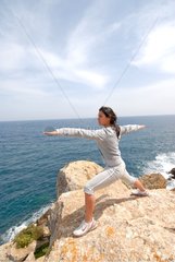 Young woman practicing yoga facing the sea Ibiza Spain