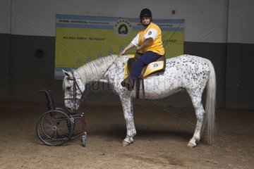Paraplegic woman on horse in a horse therapy center