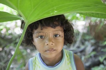 Child protected from rain with a leaf - Brazil