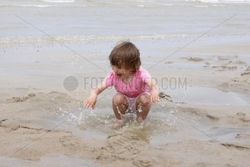 Mädchen zwei Jahre spielen mit dem Wasser am Strand Frankreich