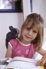 Fillette faisant ses devoirs avec un lapin nain sur l'épaule