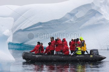 Tourists in inflatable boat beside an iceberg Antarctica