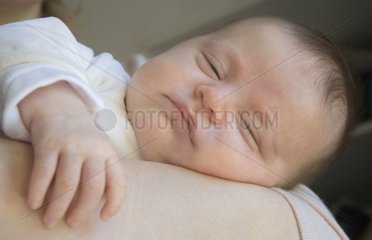Visage d'un bébé dormant dans les bras de sa mère