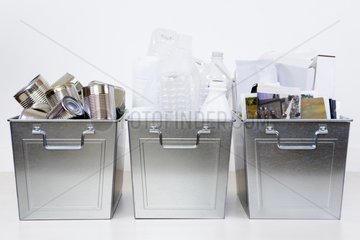 Three steel bins containing recyclable items