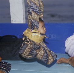 Baby balanciert sich in einem Tuch in einem Boot aus