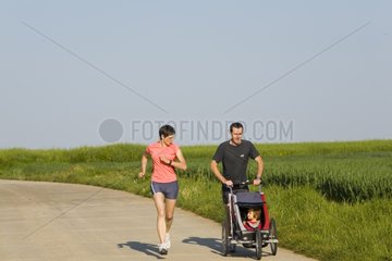 Parents current pushing their daughter in a stroller