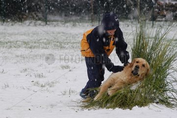 Golden Retriever Kind und Hund spielen im Schnee Frankreich