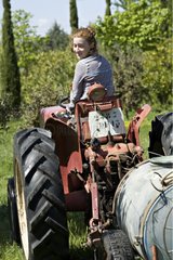 Young red-haired girl on a tractor in a garden