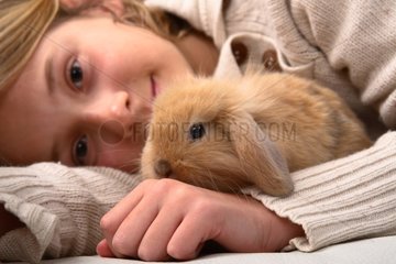 Young girl and rabbit lying on a bed