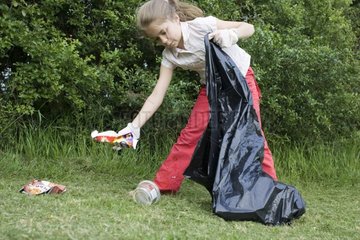 Young girl collecting discarded litter in a park UK