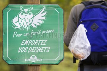 Hiker carrying a bag of waste and panel NFB France
