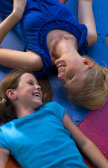 Mother and daughter relaxing together laying on colorful ride andf laughing together outside in park