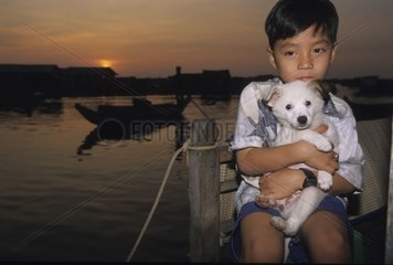 Chiot sur les genoux d'un garçon Lac Tonle Sap Cambodge