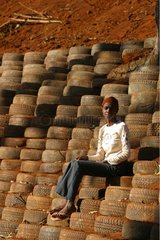 Enfant assis sur un mur de soutènement en pneus usés Mayotte