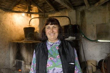 Bulgarian woman distilling fruit alcohol in a still
