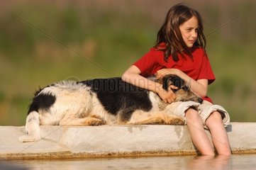 FIllette avec un chien bâtard au bord d'un bassin