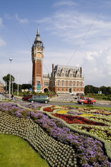 Colorful flowers in sunshine of beautiful Hotel de Ville architecture in small Frence village of Calais France
