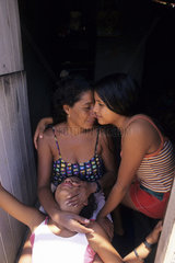 Latin America  Brazil. Happy half-breed  dark-skinned family. Family togetherness in a low income situation. Mother and daughters  balance  balancing  harmony  equilibrium  happy family