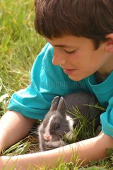 Enfant et lapin gris et blanc couchés dans l'herbe