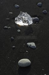 Ice block and pebbles on black sand Joekulsárlón Iceland