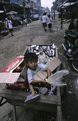 Ein Junge  der in einer Schubkarre voller Dosen Kambodscha sitzt