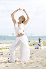 Woman and man praticing yoga on a beach in Martinique Island