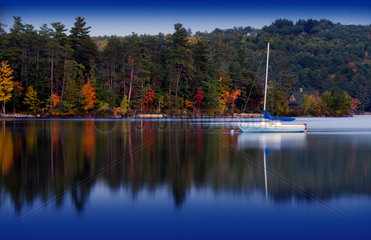 Peaceful quiet scene of lake and small boat in Long Lake in Bridgton Maine in New England colorful scene with reflections