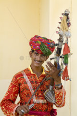 Young man in traditional costume playing old fashioned guitar instrument called a sarangi in Agra India