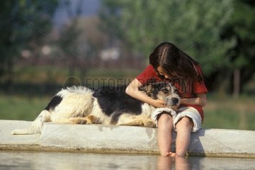 Mädchen kuschelte einen Bastardhund am Rand eines Frankreichbeckens