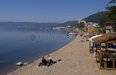 Beautiful relaxed people on shore with boats at Listvyanka in Lake Baikal near Irkutsk in Siberia Russia