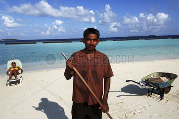Maldives  man cleaning the beach