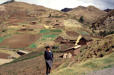 Peru  A girl standing in a landscape of a rural village with farmland around. The use for farming causes erosion.