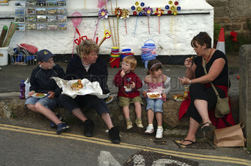 Cornwall  family eating fish and chips in Mousehole village