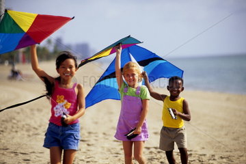 Young children with kites at beach age 6 and 4 multi ethnic Asian Black and white