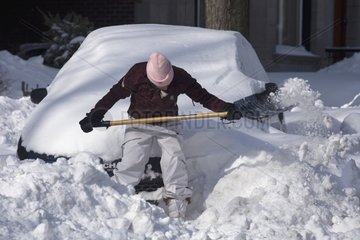 Girl clearing of snow her car after a snow storm Montreal