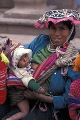 Woman in traditional clothe nursing her baby Peru