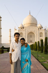 Local Hindu couple taking portrait on holiday in front of the famous Taj Mahal one of the wonders of the world in Agra India