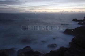 Schaum am felsigen Ufer des Ile de Bannec in Twilight
