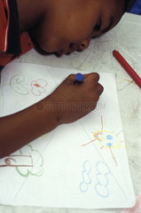 Black child in classroom drawing nature elements ( sun  clouds  trees  flower ). education  school  painting.