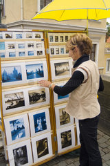 Retired woman shopping for paintings on the famous Charles Bridge in Prague Czech Republic