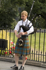 Colorful young man playing bagpipes in capital of Edinburgh Scotland
