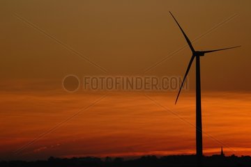 Windmühle mit der schlafenden Sonne und Kirche am Horizont Frankreich