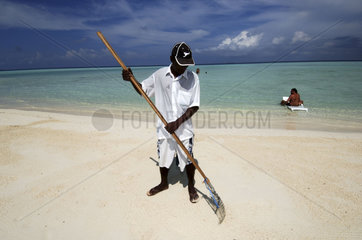 Maldives  a servant cleaning the beach