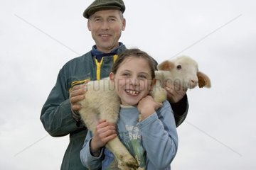 Stockbreeder und seine Tochter hält ein Lamm auf ihren Schultern