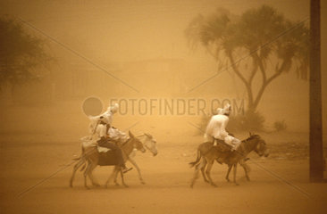 Sudan  Nfala. Men riding on donkeys through sandstorm.