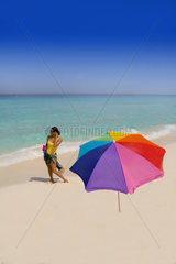 Young Hispanic woman with umbrella on the colorful beaches of Cancun Mexico