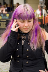 Alternative woman on cell phone with purple hair in tourist city of Cesky Krumlov in Czech Republic