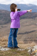 Little Girl watching with binoculars in dry hills