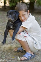 Boy tenderly tightening an old Pug in his arms France